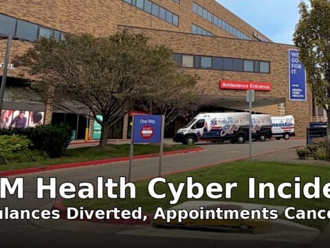 Ambulances at the St. John Hospital emergency entrance in Detroit, with the headline UNM Health Cyber Incident: Ambulances Diverted, Appointments Cancelled overlaid